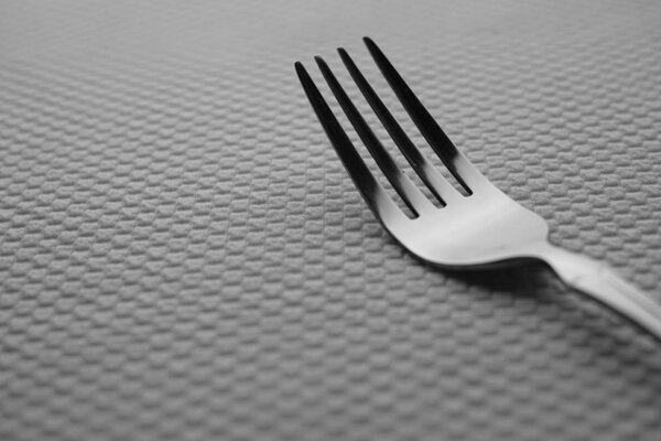 Modern silver stainless steel fork on a white table.