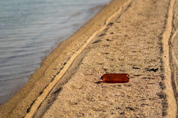 Prázdná plastová láhev ležící na písečné pláži. znečištění životního prostředí. — Stock fotografie
