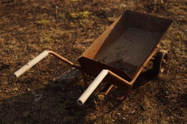 Tekerlekli eski paslı tramvay kuru otlarla yerde duruyor..