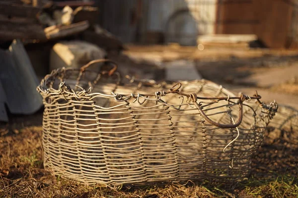 Cesta de vime velha feita de fio de alumínio em uma jarda rural . — Fotografia de Stock