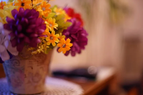 Пышный букет искусственных цветов в цветочном горшке стоит на столе в гостиной . — стоковое фото
