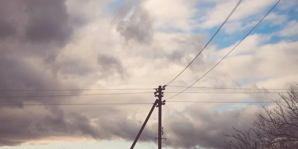 Elektrische paal. De draden hebben de vorm van een driehoek. Bewolkte lucht. — Stockfoto