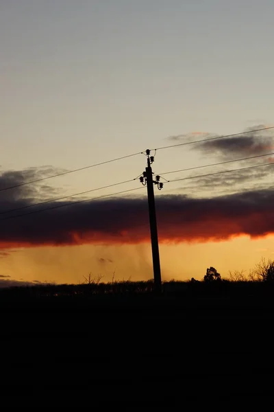 Torre elétrica de alta tensão silhueta no céu do por do sol . — Fotografia de Stock