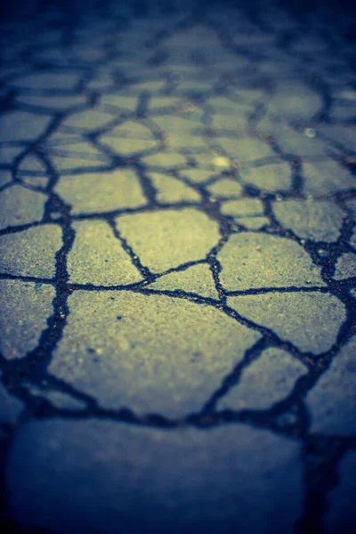 Old road surface made of old asphalt with cracks. Dark blue yellow tone. — 图库照片