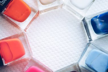 Nail polish set. Glass bottles of different colors on a white table.