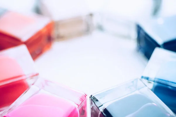 Set of nail polishes. The lower parts of glass bottles of different colors on a white table. — Stockfoto