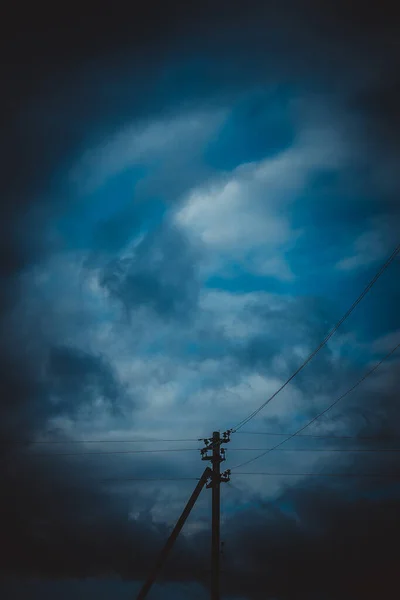 Electric pole in dark blue cloudy sky. — ストック写真