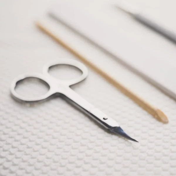 Sada nástrojů pro manikúru na stole. Nůžky, pilník na nehty, oranžová tyčinka, lopatka. — Stock fotografie