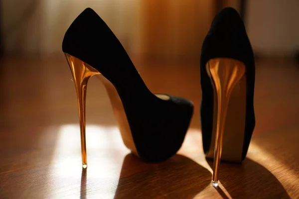 Mode schwarze Damenschuhe auf goldglänzendem High Heel in sonnigem Raum. — Stockfoto