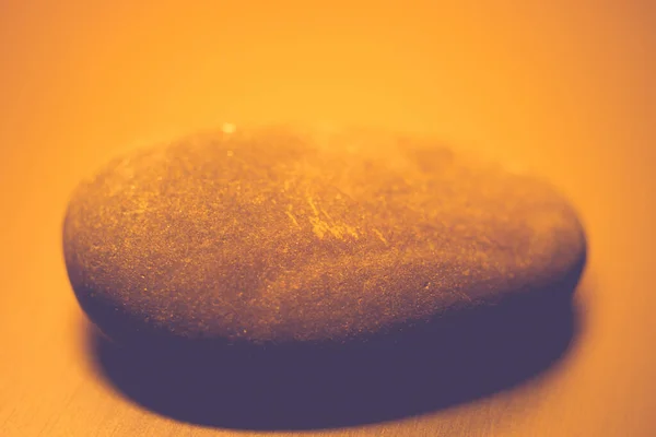 Una gran piedra de guijarro sobre la mesa, luz naranja . — Foto de Stock