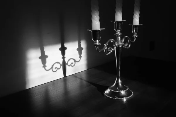 Klasyczny świecznik z trzema świecami, odbicie cienia na ścianie. Czarno-białe zdjęcie. — Zdjęcie stockowe
