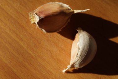 Güneşli ahşap masanın kabuğunda iki sarımsaklı karanfil..
