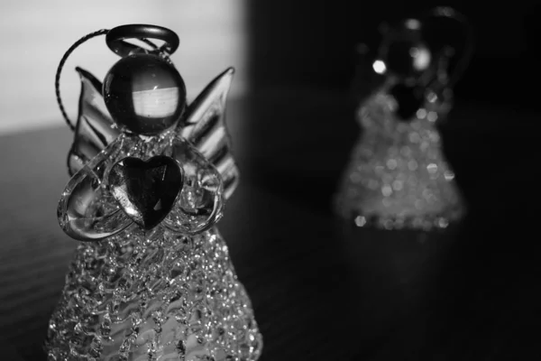 Two small statues of angels on the table, light with dark, black and white photo. — Stockfoto