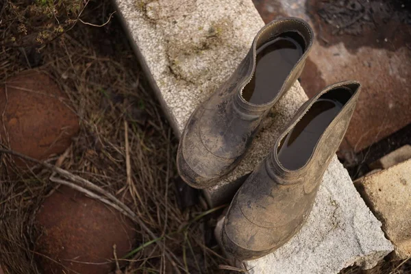 Un paio di vecchie galosce sporche con dentro dell'acqua su mattoni . — Foto Stock