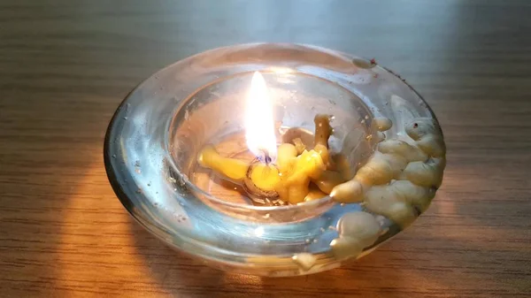 Низкая свеча горит в грязном круглом стеклянном подсвечнике — стоковое фото