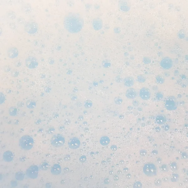 Weißer Schaum mit Blasen, die in blauem Wasser auftauchen. Ansicht von oben. — Stockfoto