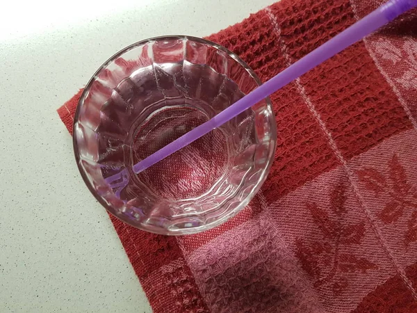 Copo cheio de água com tubo de beber em uma toalha vermelha . — Fotografia de Stock