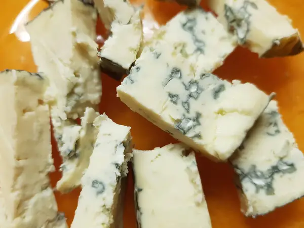 Trozos de queso dorblu en un plato de naranja, primer plano —  Fotos de Stock