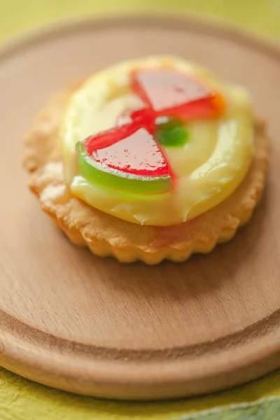 Sweet round cake with yellow cream and red jelly watermelon slices on wooden board
