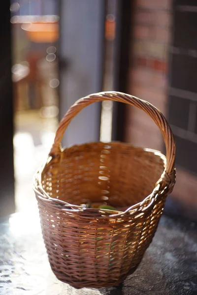 A wicker basket of whole vines stands on the glass table of the veranda. Household items.