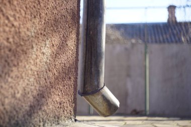 Kırsal evin köşesindeki eski drenaj borusu..