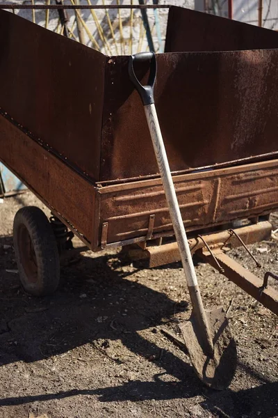 农村院子里的一辆肮脏的铲子站在一辆生锈的拖车旁边 花园工具 — 图库照片