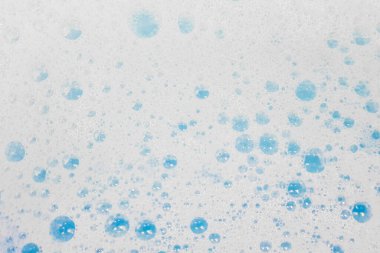 White foam with bubbles popping in blue water
