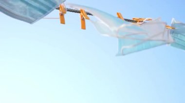 Mavi tıbbi maskeler, çamaşır ipinde asılı ve gökyüzüne çiviler takılı.