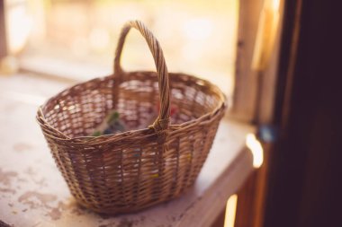 Eski güneşli pencere pervazında hasır bir sepet duruyor.