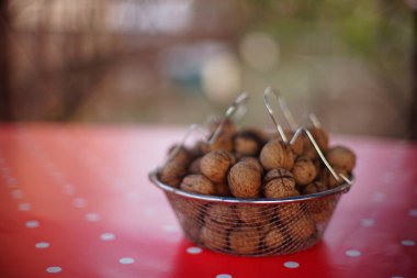 Kırmızı masa örtüsünde beyaz noktalı ceviz dolu bir kase..