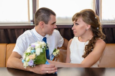 Windows tarafından köşe standında gülümseyen yeni evliler oturmak