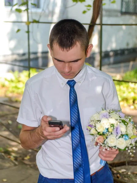 Man with a bouquet of flowers chatting on a mobile — Stock Photo, Image