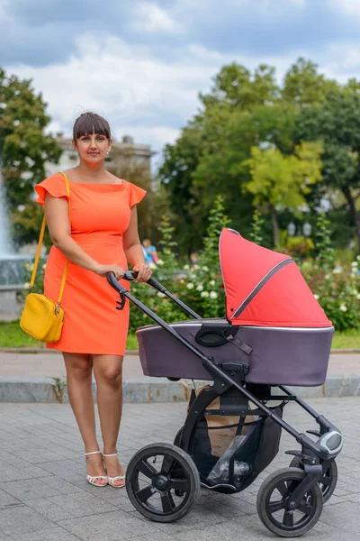 Mother attending to her infant baby in a pram — Stock Photo, Image