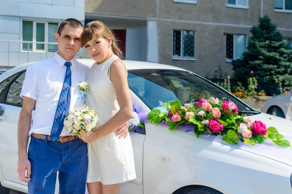 Joven pareja de novias de pie cerca del coche — Foto de Stock