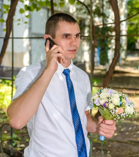 Hombre con un ramo de flores charlando en un móvil — Foto de Stock