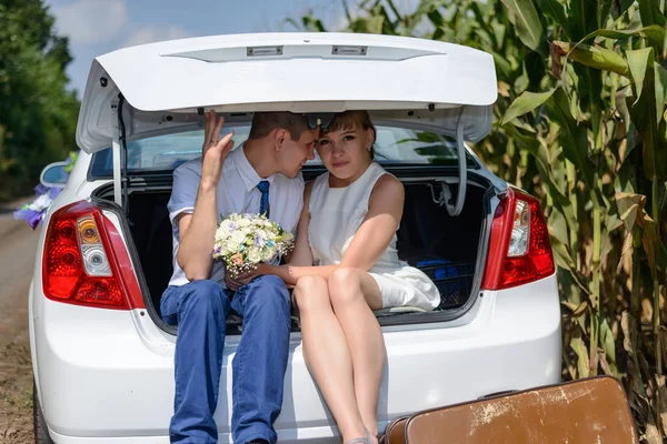 新婚夫婦の車のトランクに座っている間にキス — ストック写真