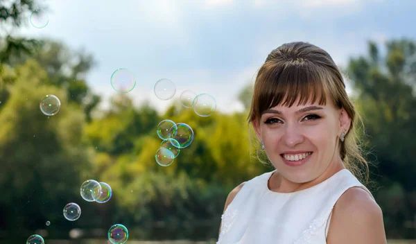 Pretty young bride watching floating bubbles — Stock Photo, Image
