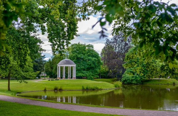 Kupolförsedda lusthus i en grönskande ark återspeglas i en sjö — Stockfoto