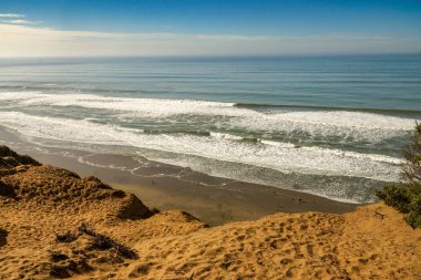 Pasifik Okyanusu dalgaları CA kumlu bir uçurumun üzerinden bakarak