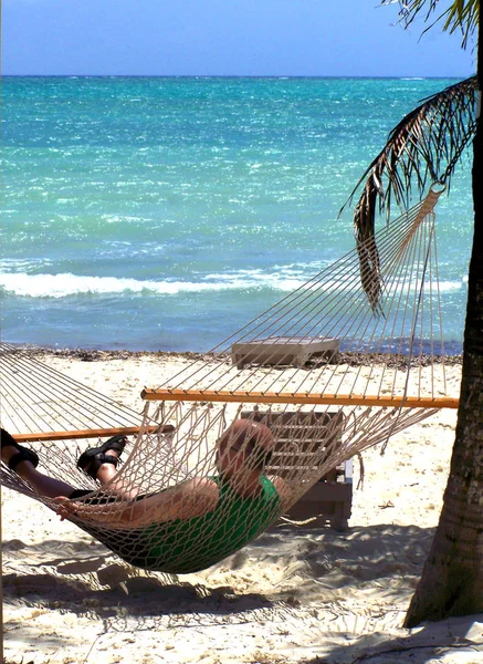 Hombre relajándose en un hermoso día soleado en la playa en una hamaca — Foto de Stock