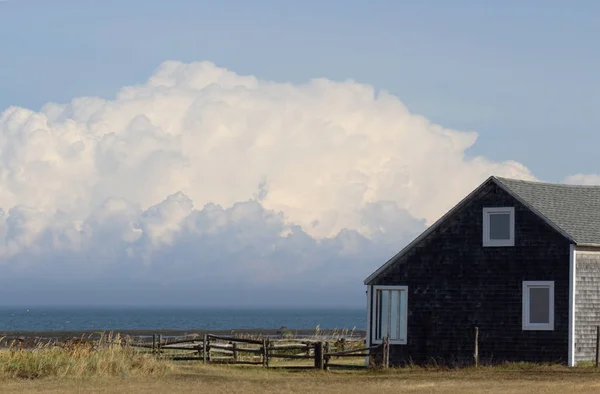 Büyük beyaz bulutlar ile deniz kenarında küçük ev