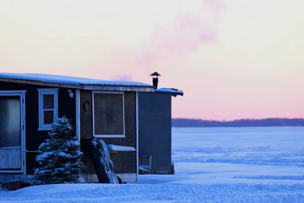 Fumare camino riscaldare la piccola capanna di pesca sul ghiaccio su un l congelato — Foto Stock