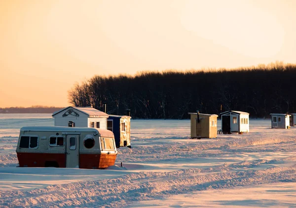 Gün batımında balıkçı kulübeleri donmuş gölde buz