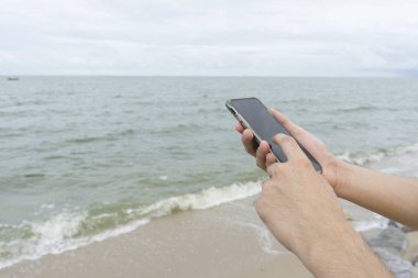 Kumsalda bir adam manifatura cep telefonu