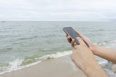 Kumsalda bir adam manifatura cep telefonu