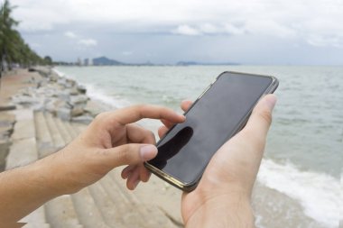 Kumsalda bir adam manifatura cep telefonu