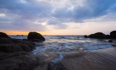 Kayalar ve dalgalar günbatımı sırasında görünümü