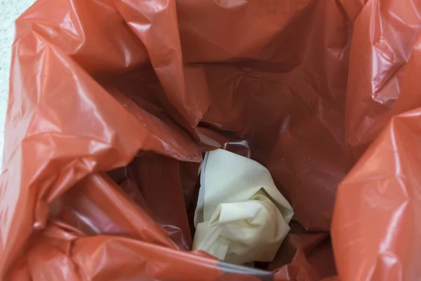 A pair of used gloves inside a red bin for garbage — Stock Photo, Image