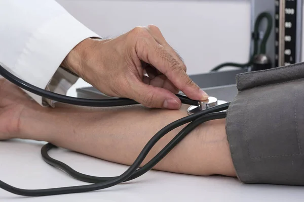 Doctor measuring blood pressure in medical office — Stock Photo, Image