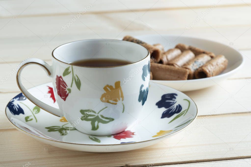 A cup of tea and coconut rolls on wooden background